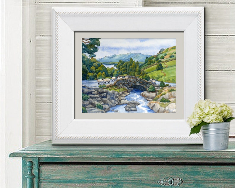 Pode incluir: Uma pintura em aquarela de uma ponte de pedra sobre um rio com ovelhas cruzando. A ponte &eacute; cercada por &aacute;rvores verdes e colinas no fundo. O c&eacute;u &eacute; azul com nuvens brancas.