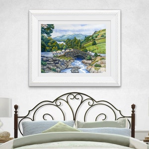Pode incluir: Uma pintura em aquarela de uma ponte de pedra sobre um rio com ovelhas cruzando-a. A ponte &eacute; cercada por &aacute;rvores verdes e colinas. O c&eacute;u &eacute; azul com nuvens brancas.