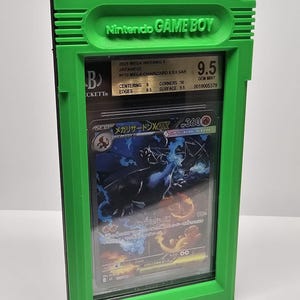 Op de afbeelding: Een groene plastic behuizing die lijkt op een Game Boy, met daarin een beoordeelde Pok&eacute;mon-kaart. De kaart heeft een Charizard-illustratie en is beoordeeld met 9,5. De behuizing heeft het Nintendo Game Boy-logo.