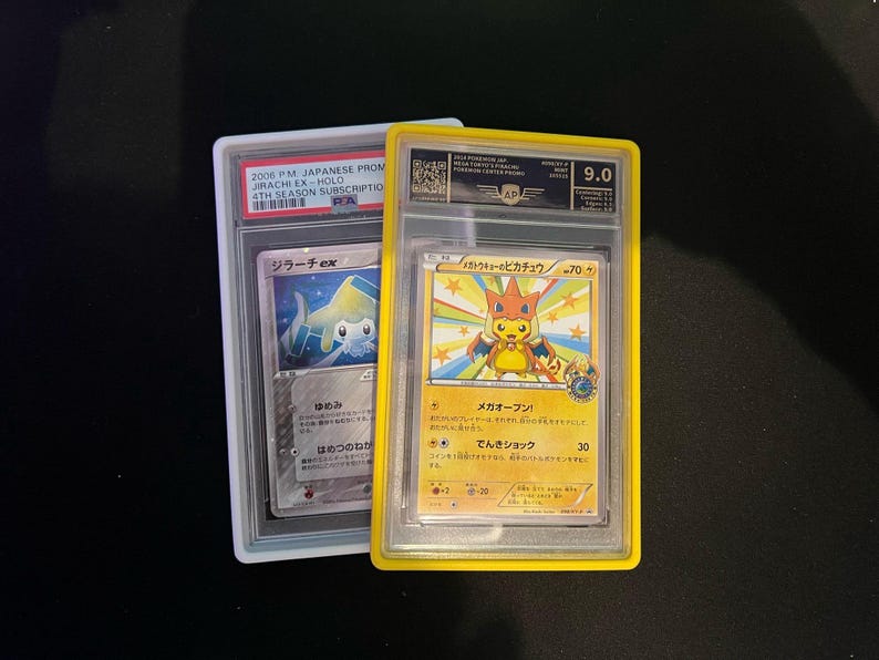 May include: Two graded Pok&eacute;mon trading cards. One card features a Jirachi EX-HOLO, and the other showcases a Pikachu character. The Pikachu card is graded 9.0. Both cards are encased in protective holders, with Japanese text visible.
