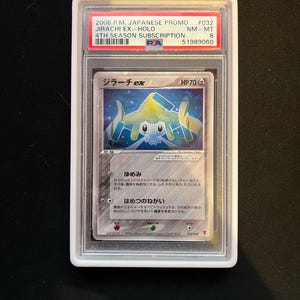 May include: A graded Pok&eacute;mon card featuring Jirachi EX-Holo from the 2006 P.M. Japanese Promo set. The card is encased in a protective holder with the text "Jirachi ex" and "HP70" visible. The card has Japanese text.