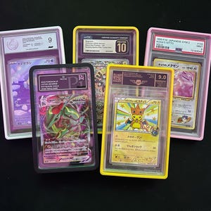 May include: Five graded Pok&eacute;mon trading cards in protective cases. The cards feature various characters and are encased in white, black, pink, and yellow holders. Each case displays a grade and other information.