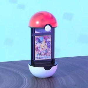 K&ouml;nnte beinhalten: Ein rot-wei&szlig;es Display im Pok&eacute;ball-Design, das eine farbenfrohe Sammelkarte h&auml;lt. Der St&auml;nder hat einen schwarzen Rahmen und einen wei&szlig;en Knopf. Die Karte zeigt verschiedene Charaktere in einer lebendigen Illustration.