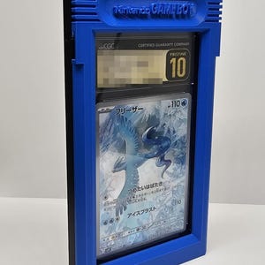 Op de afbeelding: Een blauwe Game Boy-stijl display case met een beoordeelde trading card. De case heeft de tekst "Nintendo GAME BOY". De kaart is beoordeeld met "Pristine 10" door CGC en heeft een illustratie.