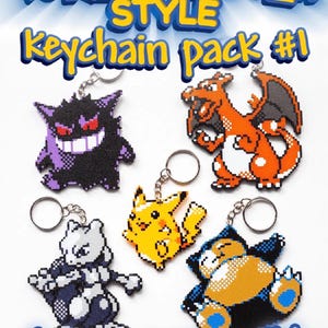 May include: A collection of five pixel art-style keychains featuring various characters. The keychains include a purple Gengar, an orange Charizard, a yellow Pikachu, a gray Mewtwo, and a blue and tan Snorlax. The text "Poke-Monster Style Keychain Pack #1" and "Gotta print 'em all!" are displayed.