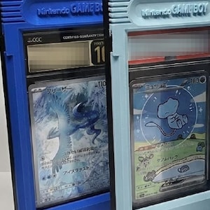 Op de afbeelding: Twee beschermende hoesjes voor verzamelkaarten, ontworpen om op Nintendo Game Boy-cartridges te lijken. E&eacute;n is blauw, de andere lichtblauw. Elke hoes bevat een kaart met Japanse tekst en illustraties. De hoesjes hebben de tekst "Nintendo GAME BOY" erop.