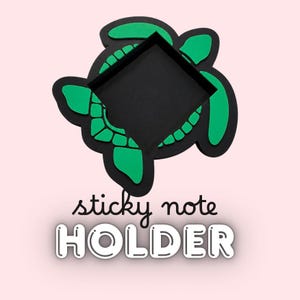 May include: A black and green turtle-shaped sticky note holder with a square center cutout. The text "sticky note" is written in a black cursive font above the word "HOLDER" which is displayed in large, bold, white outlined letters.