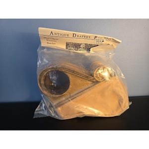 May include: A brass-colored Mini Classic Keystone Bracket, packaged in a clear plastic bag. The packaging includes the text "Antique Drapery Pro Co."