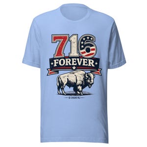May include: A light blue t-shirt featuring a graphic with the text 716 FOREVER. The number 716 includes a red, white, and blue American flag pattern. Below the text is a detailed illustration of a bison, with the copyright text 2026 RJ.