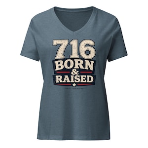 May include: A heathered blue V-neck t-shirt featuring a distressed graphic print that reads 716 BORN & RAISED in large white and dark blue lettering, accented with a small star and the text 2026 RJ centered at the bottom of the design.