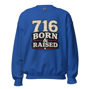 May include: A royal blue long-sleeve sweatshirt featuring a distressed graphic print that reads 716 BORN & RAISED in white and navy blue lettering, with a small white star and the text 2026 RJ centered below the main design.