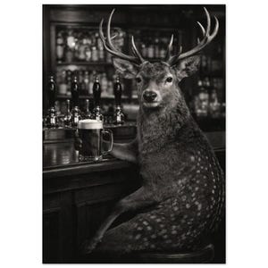 May include: A black and white photographic print featuring a deer with large antlers sitting at a bar counter. The deer is holding a glass mug filled with dark beer. The background shows a blurred bar setting with multiple beer taps and bottles.