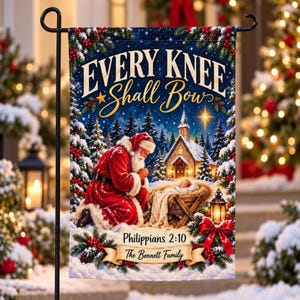 May include: A rectangular garden flag featuring a snowy winter scene with Santa Claus kneeling before a manger containing a baby. The text reads Every Knee Shall Bow, Philippians 2:10, and The Bennett Family. The design includes pine branches, red berries, a church, and a lantern.