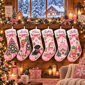 Op de afbeelding: Zes witte kerstsokken met roze geruite boorden, gepersonaliseerd met de namen Natalynn, Amelia, Clara, Sophia, Avery en Bella. De sokken zijn voorzien van feestelijke illustraties, waaronder een kerstboom, een meisje, een hond, een hobbelpaard, een kasteel en een notenkraker.