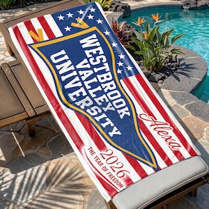 May include: A personalized beach towel with a patriotic design. The towel features the text "Westbrook Valley University" in a blue banner, with red and white stripes, stars, and the name "Alexa". The year "2026" is also printed on the towel.
