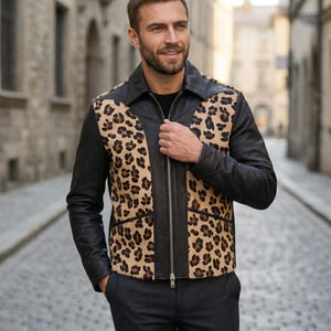 Könnte beinhalten: Eine Jacke mit schwarzem Lederkragen, Ärmeln und einem vorderen Mittelteil mit durchgehendem silberfarbenem Reißverschluss. Die Seitenteile zeigen ein beiges und braunes Leopardenmuster. Das Kleidungsstück wird über einem schwarzen Oberteil und einer dunklen Hose getragen.