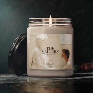 May include: A white ceramic mug with a black handle and the text "But First, Coffee" in a bold, black font. The mug is set against a blurred background, suggesting a cozy setting.