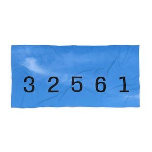 May include: A blue rectangular towel with the numbers 32561 printed in black. The towel has a cloudy sky design.