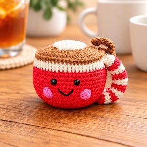 Peut inclure: Un jouet en peluche crocheté en forme de tasse rouge vif avec un dessus marron, doté d'un bord blanc, de deux yeux en perles noires, d'un sourire noir brodé et de joues roses. L'anse est rayée rouge et blanc avec une petite boucle marron.