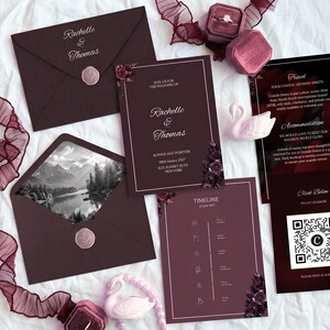 May include: A dark burgundy wedding stationery set featuring an invitation, a timeline card, and an information card with a QR code. The set includes envelopes with wax seals, one showing a black and white mountain landscape, and two swan figurines.