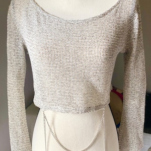 Puede incluir: Una taza de cerámica blanca con un asa negra y el texto "But First, Coffee" en negrita negra. La taza se encuentra sobre un fondo borroso, sugiriendo un ambiente acogedor.