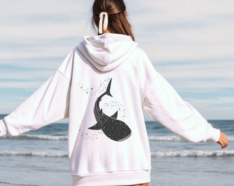 May include: White hoodie with a black and white whale shark graphic on the back. The shark is swimming upwards with a starry sky pattern.