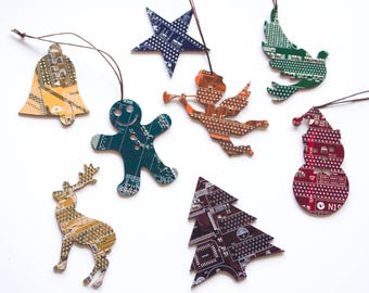 May include: A collection of Christmas ornaments in various shapes, including a bell, star, angel, gingerbread man, dove, snowman, reindeer, and Christmas tree. Each ornament is made from recycled circuit boards, featuring a mix of colors and intricate electronic patterns.