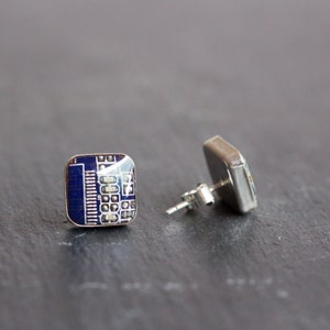 Op de afbeelding: Vierkante oorstekers met een blauw en wit printplaatontwerp. De oorbellen hebben een zilverkleurige metalen achterkant en pin. Het printplaatontwerp is zichtbaar aan de voorkant.