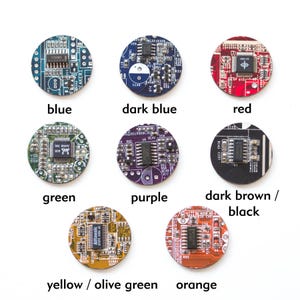 May include: A collection of nine circular circuit board components in various colors, including blue, dark blue, red, green, purple, dark brown/black, yellow/olive green, and orange. Each component has integrated circuits and text labels.