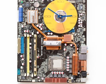 Wandklok gemaakt van donkerbruin moederbord met unieke gele en koperen details, klaar voor verzending