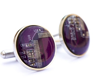 May include: Silver cufflinks featuring a purple circuit board design. The round faces have a gold-coloured rim and silver posts. The circuit board design includes the numbers "128", "C61", "252", "253", and "51".
