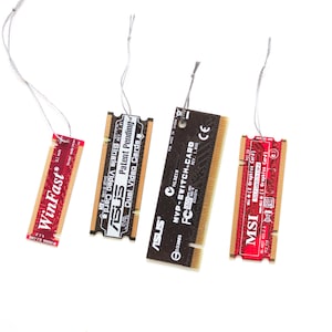 May include: Four computer component ornaments, including a red WinFast card, an ASUS card with "Patent Pending" text, a black MVP-SWITCH-CARD, and a red MSI card. Each card is rectangular and has a silver string attached for hanging.
