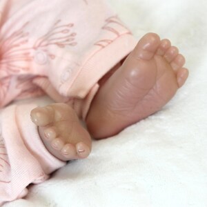 A baby doll peacefully sleeps, dressed in a soft pink outfit, exuding a sense of calm and innocence.