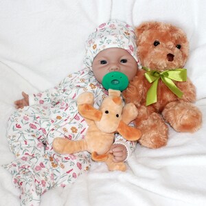 A baby doll lies on a colorful blanket next to a teddy bear, evoking a sense of warmth and childhood comfort.