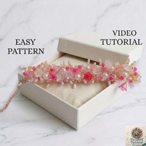 May include: A beaded floral bracelet in a white box. The bracelet features pink, white, and clear beads, with accents of gold. The text "EASY PATTERN" and "VIDEO TUTORIAL" are visible.