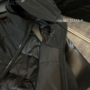 May include: Black hooded jacket with the brand name "Arc'teryx" printed on the hood. The jacket has a full zipper and a quilted interior. The jacket is made of a smooth, matte material.