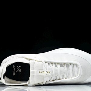 Puede incluir: Una zapatilla deportiva blanca de perfil bajo, con dise&ntilde;o de cordones y puntera redondeada. La zapatilla tiene el nombre de la marca "Arc'teryx" impreso en el lateral. La zapatilla est&aacute; hecha de una combinaci&oacute;n de materiales, incluyendo malla y cuero sint&eacute;tico.