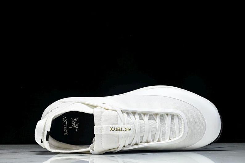 Puede incluir: Una zapatilla deportiva blanca de perfil bajo, con dise&ntilde;o de cordones y puntera redondeada. La zapatilla tiene el nombre de la marca "Arc'teryx" impreso en el lateral. La zapatilla est&aacute; hecha de una combinaci&oacute;n de materiales, incluyendo malla y cuero sint&eacute;tico.
