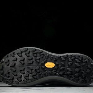 Puede incluir: Suela de zapatilla deportiva negra con un patr&oacute;n texturizado y un logotipo amarillo de Vibram. La suela est&aacute; dise&ntilde;ada para la tracci&oacute;n y la durabilidad, adecuada para actividades al aire libre. El calzado es probablemente para correr o caminar.