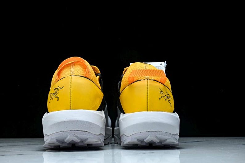Puede incluir: Par de zapatillas deportivas amarillas y negras con suelas blancas. Las zapatillas tienen un contrafuerte de tal&oacute;n amarillo con un gr&aacute;fico negro y una suela blanca con un patr&oacute;n texturizado. Las partes superiores son una combinaci&oacute;n de amarillo y negro.