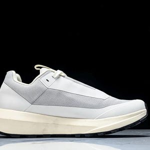 May include: White and gray athletic shoe with a thick, off-white sole and black tread. The shoe features a mesh upper and a streamlined design, suitable for various activities.