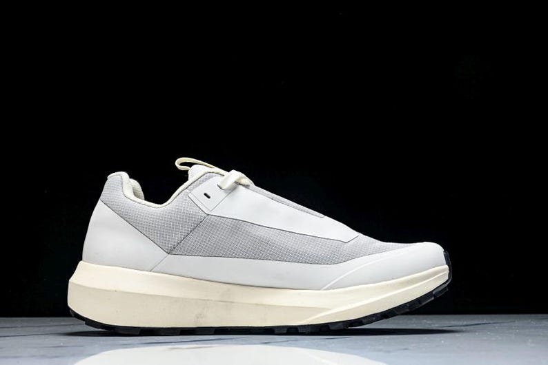 May include: White and gray athletic shoe with a thick, off-white sole and black tread. The shoe features a mesh upper and a streamlined design, suitable for various activities.