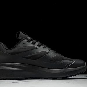 May include: All-black athletic shoe with a thick sole. The shoe features a mesh upper and a textured design. The laces and sole are also black. The shoe is designed for running or other athletic activities.
