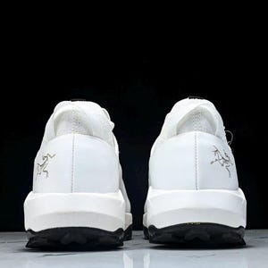 Puede incluir: Un par de zapatillas blancas con suelas negras, visto desde atr&aacute;s. Los zapatos tienen un dise&ntilde;o minimalista, talones texturizados y un peque&ntilde;o logotipo. Las suelas negras est&aacute;n texturizadas para el agarre.