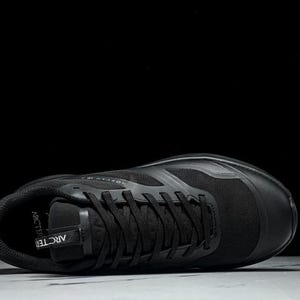 May include: A black athletic shoe with black laces and a mesh upper. The shoe is lying on its side, with the sole facing up. The word "ARCTERYX" is visible on the shoe's tongue.