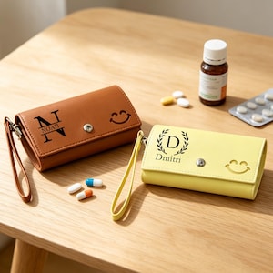 May include: A brown rectangular pouch with a wrist strap, a snap closure, and the letter N with the name Noah printed on it, alongside a yellow pouch with a wrist strap, a snap closure, and the letter D with the name Dmitri printed on it.