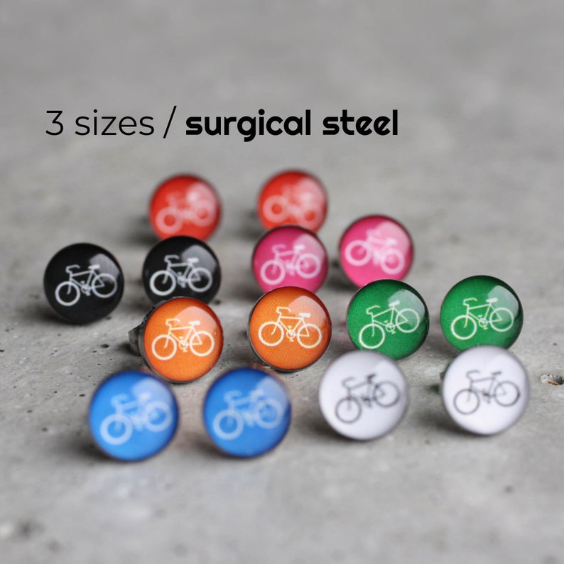 May include: A set of 12 surgical steel earrings with a bicycle design. The earrings come in a variety of colors, including black, orange, green, pink, red, and blue. The text "3 sizes / surgical steel" is visible in the image.