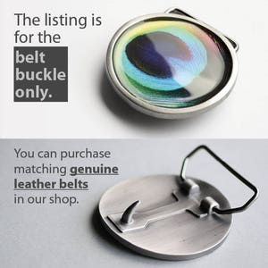 May include: A silver belt buckle with a round, peacock feather design. The buckle has a silver finish and a smooth surface. The peacock feather design is colorful and vibrant, with shades of blue, green, and yellow. The buckle is designed to be used with a belt.