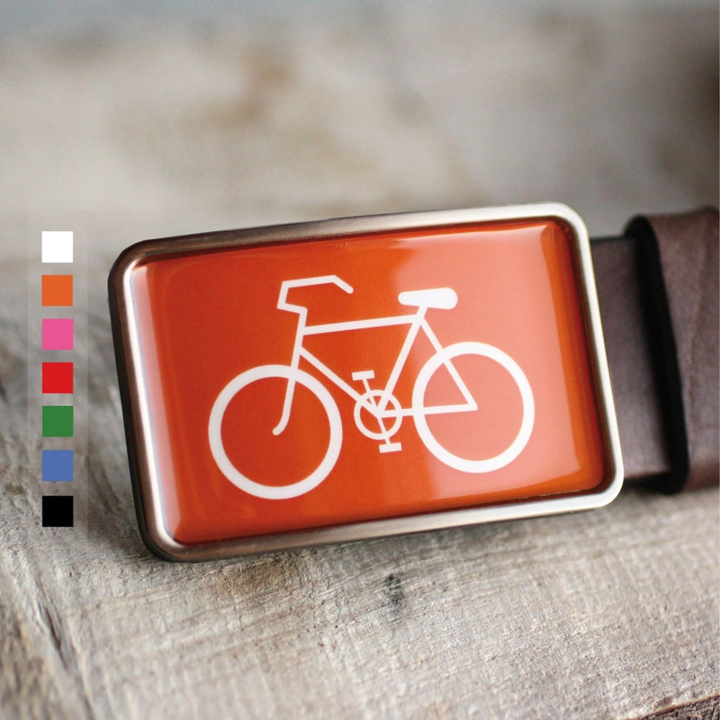 Peut inclure: Une boucle de ceinture argent&eacute;e avec un fond orange vif et une silhouette blanche d'un v&eacute;lo.