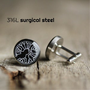 May include: A pair of cufflinks made of 316L surgical steel. One cufflink features a black background with a white tree of life design.